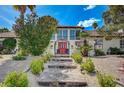 Inviting two-story home with mature trees, manicured landscaping, and a charming walkway leading to a red entryway at 3151 Coachlight Cir, Las Vegas, NV 89117