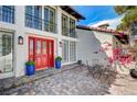 Beautiful home featuring a red front door, well-kept landscaping, and a cozy seating area on a brick-paved patio at 3151 Coachlight Cir, Las Vegas, NV 89117