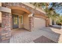 Welcoming home entrance with stone pillars, arched entry, and a paver driveway leading to a two-car garage at 5239 Tartan Hill Ave, Las Vegas, NV 89141