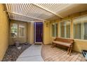 Inviting front entryway with a covered porch, stylish seating, and a striking purple front door at 7349 Royal Melbourne Dr, Las Vegas, NV 89131