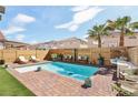 Beautiful pool with brick trim, adjacent to lush landscaping, offers a serene backyard oasis at 7566 Hope Valley St, Las Vegas, NV 89139