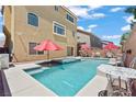 A backyard swimming pool and a jacuzzi are furnished with lounge seating and red umbrellas at 9742 Toad Hollow St, Las Vegas, NV 89141