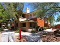 Exterior of apartment building with tan and orange paint and sidewalks surrounded by trees at 1000 Duckhorn Ct # 102, Las Vegas, NV 89144