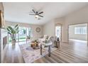 Bright living room featuring modern decor, wood floors, a ceiling fan, and sliding glass doors to the backyard at 10205 Birch Bluff Ln, Las Vegas, NV 89145