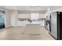 Bright kitchen with white cabinetry, stainless steel appliances, center island, and sliding door access to the outdoor area at 11074 Caramel Crest Ct, Las Vegas, NV 89135