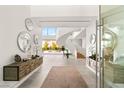 Bright foyer showcasing a sweeping staircase, modern decor, and seamless indoor-outdoor transition at 13 Rockstream Dr, Henderson, NV 89012