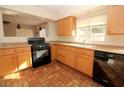 Well-lit kitchen featuring wood cabinets and black appliances at 1467 Hialeah Dr # C, Las Vegas, NV 89119