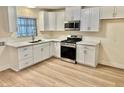 Modern kitchen featuring white cabinets, quartz countertops, stainless steel appliances and wood flooring at 3037 Holly Hill Ave, Las Vegas, NV 89104
