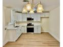 Bright kitchen featuring white cabinets, stainless steel appliances, quartz counters and a modern chandelier at 3037 Holly Hill Ave, Las Vegas, NV 89104