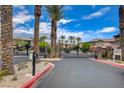 Gated entry to a residential community with desert landscaping and mature palm trees at 6868 Sky Pointe Dr # 1089, Las Vegas, NV 89131