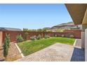 Spacious backyard featuring green grass, brick patio, privacy fence, and mountain views at 10693 Harvest Green Way, Las Vegas, NV 89135