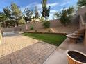 A spacious backyard with brick pavers, a small patch of grass, a rock water fountain, and tasteful landscaping at 2947 Caxton Grove Dr, Henderson, NV 89052