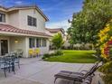 A cozy backyard patio with furniture and lush green lawn and colorful flowering shrubs at 390 Rushing Creek Ct, Henderson, NV 89014