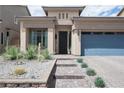 Striking front entrance features desert landscaping, a gray brick driveway and walkway, and a contemporary style front door at 5850 Rockway Glen Ave, Las Vegas, NV 89141