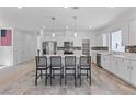 Open kitchen with an island, stainless steel appliances, tile backsplash, and sleek white cabinets at 5937 W Frias Ave, Las Vegas, NV 89141