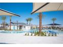 Resort-style pool with palm trees, lounge chairs, and shade structures on a sunny day at 7003 Crimson Shadow St, North Las Vegas, NV 89086