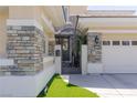 A beautifully landscaped entrance gate framed with stone accents leads to the home's front door and three-car garage at 712 Proud Eagle Ln, Las Vegas, NV 89144