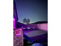 Night view of a backyard featuring a grass lawn, a small playground, a tree, and perimeter brick wall at 740 Omaggio Pl, Henderson, NV 89011