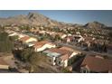 An aerial view highlights a home with mountain views in a well-maintained neighborhood with red tile roofs at 10717 Grand Cypress Ave, Las Vegas, NV 89134