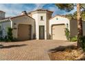 Home with dual garages featuring a brick driveway, a decorative door, and beautiful stonework on the facade at 11830 Kingsbarns Ct, Las Vegas, NV 89141