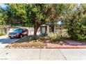 Charming single-story home with mature landscaping and a tree providing shade over the front yard and driveway at 2600 E Owens Ave, North Las Vegas, NV 89030