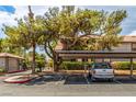 Exterior condo parking area with mature trees and landscaping, carports with parked truck and gate to residential complex at 2606 Durango Dr # 181, Las Vegas, NV 89117
