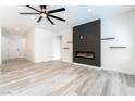 Open-concept living room with a contemporary fireplace, floating shelves, and stylish light wood flooring at 2651 Solera Moon Dr, Henderson, NV 89044