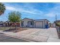 View of the charming home with a fenced front yard, mature tree, and a spacious driveway at 4432 Ash Ave, Las Vegas, NV 89110