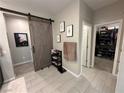 Stylish hallway with a sliding barn door, tile flooring, and access to a closet with custom shelving at 10142 Skye Saddle Ave, Las Vegas, NV 89166