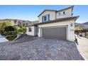 View of a modern two-story home with a paver driveway and attached garage at 12705 Coastline Shadow St, Las Vegas, NV 89141