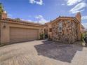 Home with brick driveway, stone details, a two-car garage, and well-maintained landscaping at 15 Avenza Dr, Henderson, NV 89011