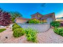Well-maintained home boasting desert landscaping, a charming stone wall, and vibrant green bushes at 2215 Bannerwood St, Henderson, NV 89044
