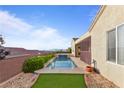 Backyard pool featuring privacy fence, desert landscaping, green turf and mountain views beyond the backyard at 2215 Bannerwood St, Henderson, NV 89044