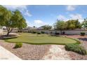 Backyard putting green surrounded by trees, shrubbery and decorative gravel provides at home recreation at 4940 Mascaro Dr, Las Vegas, NV 89122