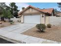 Single-story home features a two-car garage, desert landscaping, terracotta roof, and white painted exterior at 5638 Morning Song Cir, North Las Vegas, NV 89031
