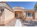 View of front entrance featuring covered front porch, tiled roof trim, tan walls, desert landscaping, and shuttered windows at 5808 Spinnaker Reach Ave, Las Vegas, NV 89130