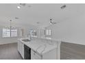 Bright kitchen featuring a large island with marble countertops, stainless steel sink, and modern black appliances at 5808 Spinnaker Reach Ave, Las Vegas, NV 89130