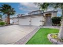 Charming home with a two-car garage, lush landscaping, and brick-lined driveway, creating curb appeal at 760 Camino La Paz, Henderson, NV 89012