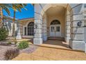 Close-up of front entrance with ornate pillars and archway, double doors and desert landscaping at 9208 November Breeze St, Las Vegas, NV 89123