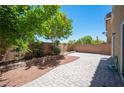 Paver patio in a backyard with a retaining wall planter, mature trees, and drought resistant rock at 9450 Niagara Landing St, Las Vegas, NV 89139