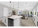 Open kitchen with a white marble island countertop, stylish pendant lighting and view to dining and living area at 10968 Tracy Stevens Ave, Las Vegas, NV 89166