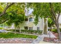 Exterior view of a condo building with green trees and landscaping, along with a rock garden at 1420 Red Crest Ln # 202, Las Vegas, NV 89144