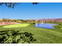 Scenic view of the lush green golf course with a tranquil pond and mountain views at 2105 Poppywood Ave, Henderson, NV 89012