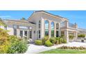 A luxurious stucco home showcasing a manicured yard, outdoor kitchen, and an abundance of windows at 2933 Red Springs Dr, Las Vegas, NV 89135