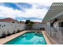 Sparkling swimming pool and hot tub in a backyard with a white pergola, fence, and desert landscaping at 3008 Blue Fin Cir, Las Vegas, NV 89128