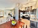 Open-concept kitchen with stainless steel appliances, dark cabinetry, and a dining area with chandelier at 3329 Hidden Ridge St, Las Vegas, NV 89129