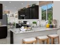 Modern kitchen featuring a breakfast bar, dark cabinets, and granite countertops at 3430 Oristano Ln, Henderson, NV 89044