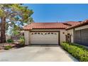 A spacious two-car garage with a concrete driveway, framed by mature trees and green shrubs at 3987 Saddlewood Ct, Las Vegas, NV 89121