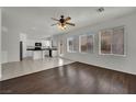 Bright living room with wood floors adjoining tiled kitchen with white cabinetry and stainless appliances at 6525 Bismark Hills St, North Las Vegas, NV 89084
