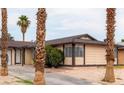 Single-story home with desert landscaping and palm trees providing a tropical feel to the front yard at 681 Pine Ridge Dr, Las Vegas, NV 89110